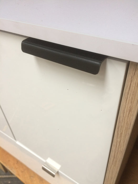 100mm matte black drawer latch attached to white cabinet